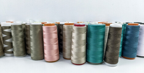 Collection of colorful sewing thread spools on a white surface.