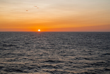 A breathtaking sunset over a calm sea, with the sky painted in warm hues of orange, pink, and...