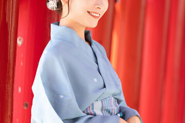  Japanese woman in yukata standing in front of a red torii gate