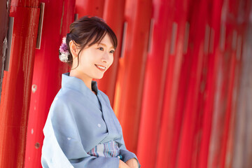  Japanese woman in yukata standing in front of a red torii gate