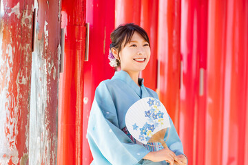  Japanese woman in yukata standing in front of a red torii gate