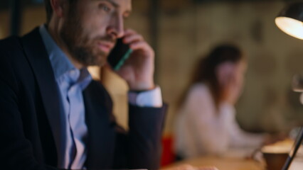 Agency coworkers calling phones working at laptops in night office closeup. 
