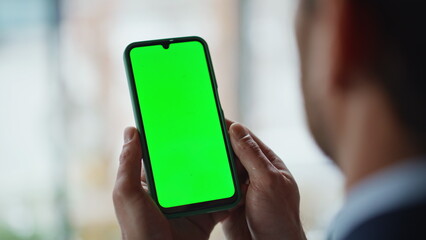 Businessman hands holding greenscreen cellphone at office workplace closeup. 