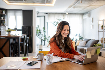 Smiling freelancer working from home using laptop at the table