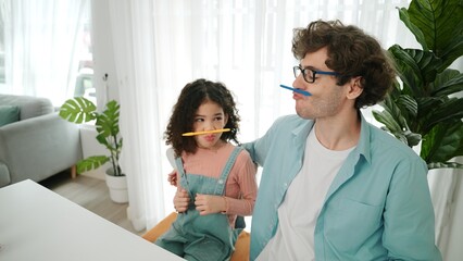Funny caucasian dad and american kid doing funny face while put pencil between lip and nose. Cute...