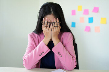 Tired and unhappy female manager is working at office with paper documents and feeling headache....