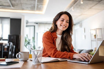 Happy entrepreneur working remotely from home office using laptop