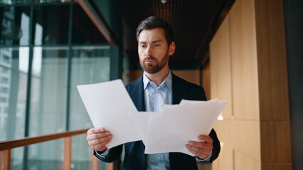 Executive examining documents excitement walking office hallway. Emotional man