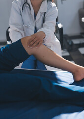 Female doctor hands doing physical therapy By extending the leg and knee of a male patient