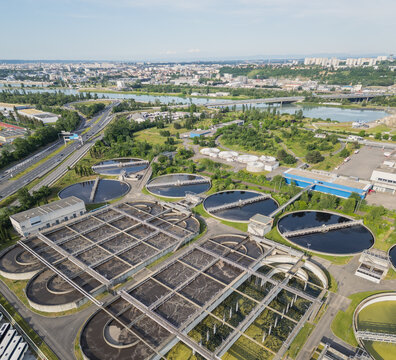 Eco-friendly aerial view of wastewater treatment plant near Lyon, France, with urban skyline &ndash; sustainable water management and environmental protection concept