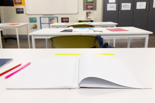 Open notebook and pencils on classroom desk, ready for school learning