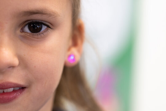 Close-up of young girl with glowing earring, smiling in school environment, copy space
