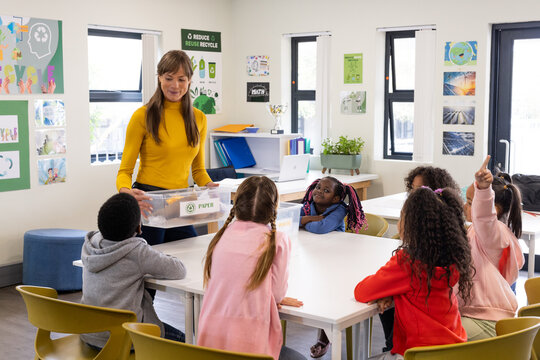 In school, female teacher discussing recycling with diverse students, engaging in learning - Powered by Adobe
