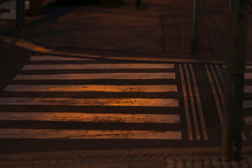 As evening falls and darkness covers the city, street lights illuminate the crosswalk, enhancing...