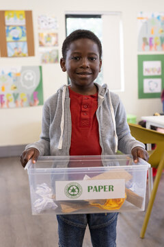 In school, african american boy holding recycling bin, learning about environmental responsibility