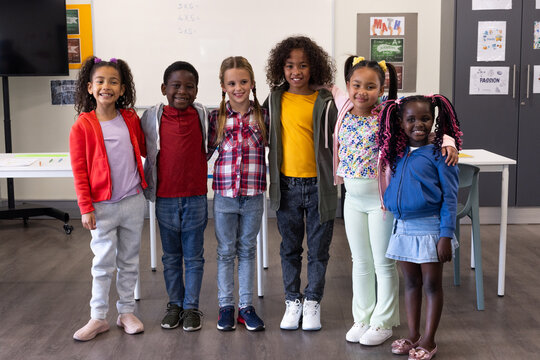 In school, diverse children standing together in classroom, embracing friendship - Powered by Adobe