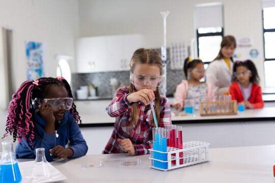 Diverse school children conducting science experiments with test tubes in classroom