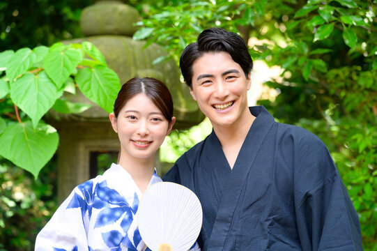 女性がうちわを手に持ち男性と並んで笑顔を見せる夏の庭園での涼しげなツーショットポートレート