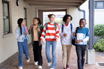 Diverse group of students walking together at school, smiling and chatting happily