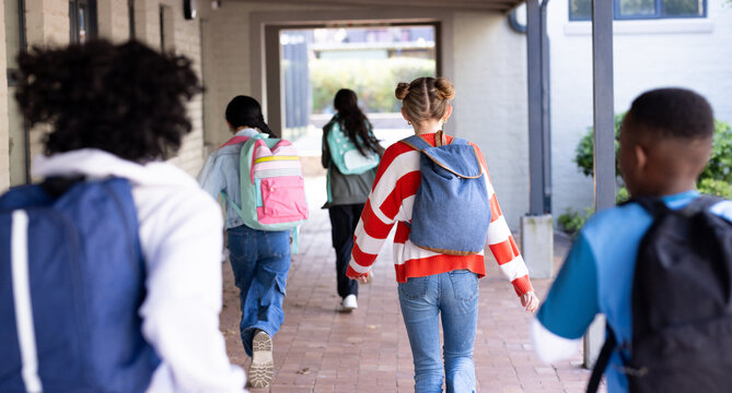 Diverse students walking together with backpacks in school hallway, enjoying their day