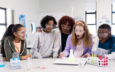 Conducting experiment in science class, diverse students observing chemical reaction, at school