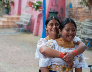 Two indigenous colombian girls embracing and smiling in guatap&eacute;