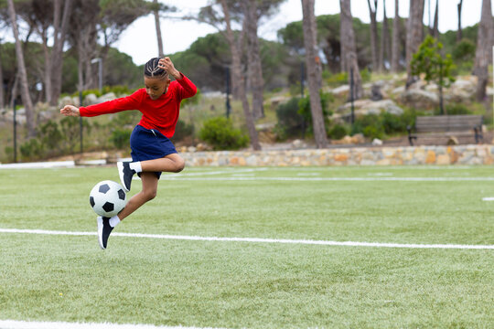 Young boy kicking soccer ball on field, showing skill and determination