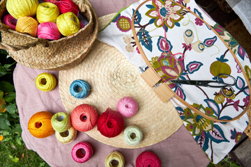 Close-up of a small garden table with embroidery supplies on a warm summer day. Colorful threads,...
