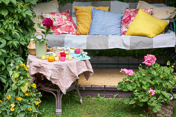 A small table covered with a soft pink cloth holds embroidery threads, a piece of fabric with an...
