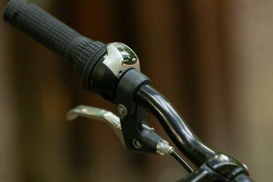 A closeup view of a bicycle handlebar is displayed in this image, highlighting a grip, a brake lever, and a bell, which are all essential components for a pleasant cycling experience