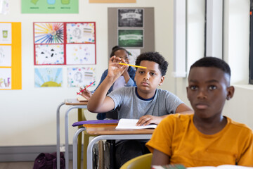 In classroom, focused boy holding pencil, listening attentively during lesson, at school