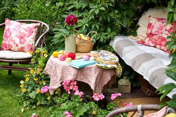 A small table covered with a soft pink cloth holds embroidery threads, a piece of fabric with an...