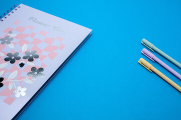 Notebook and pastel pens on blue background
