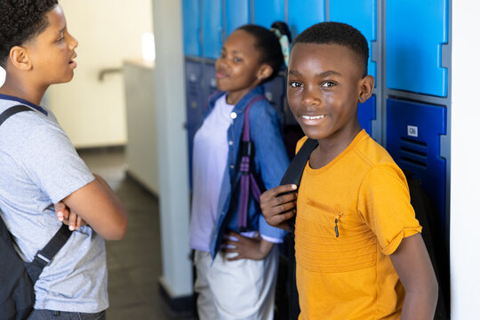 diverse students chatting by lockers, smiling and enjoying school break - Powered by Adobe