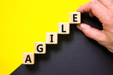 Agile symbol. Concept word Agile on beautiful wooden blocks. Beautiful yellow and black background. Businessman hand. Business agile concept. Copy space.