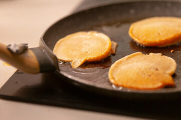 Three delectable pancakes are sizzling away on a hot skillet, showcasing the delightful cooking...