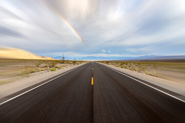 Asphalt road to horizon with rainbow and blur.