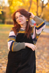 Portrait of a young beautiful red-haired girl in an autumn city park.