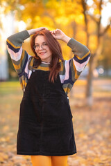 Portrait of a young beautiful red-haired girl in an autumn city park.