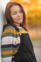 Portrait of a young beautiful red-haired girl in an autumn city park.