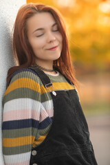 Portrait of a young beautiful red-haired girl in an autumn city park.