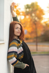 Portrait of a young beautiful red-haired girl in an autumn city park.