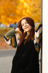 Portrait of a young beautiful red-haired girl in an autumn city park.