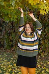 Portrait of a young beautiful red-haired girl in an autumn city park.