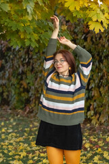 Portrait of a young beautiful red-haired girl in an autumn city park.