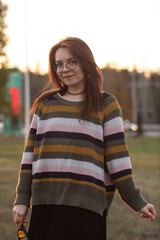 Portrait of a young beautiful red-haired girl in an autumn city park.