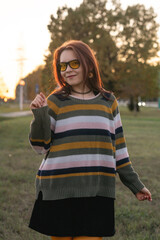 Portrait of a young beautiful red-haired girl in an autumn city park.