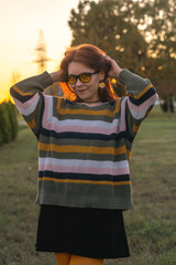 Portrait of a young beautiful red-haired girl in an autumn city park.