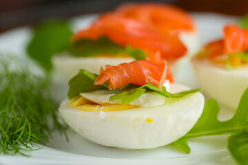 Boiled eggs with pieces of fish and herbs on top