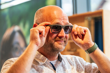 Happy man with bald head and sun glasses at shop 
